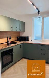 una cucina con armadi verdi, lavandino e finestra di Premium Apartment Turda a Turda