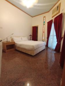 een slaapkamer met een bed, een tafel en een raam bij Qurum Heights Hotel in Muscat