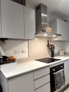 a kitchen with white cabinets and a stove top oven at Redheema in Lower Sydenham Station