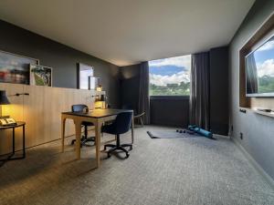 a room with a desk and a table and a window at Pullman Sao Paulo Guarulhos Airport in Guarulhos