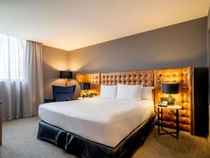 a hotel room with a large bed and two lamps at Pullman Sao Paulo Guarulhos Airport in Guarulhos +81 photos