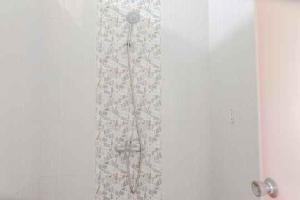 a shower in a bathroom with a white wall at FIVE HOTEL Sarangan in Sarangan