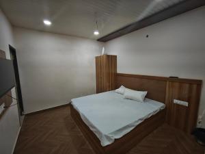 a bedroom with a bed with white sheets on it at Hotel aditya palace in Padrauna