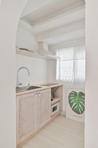 a white kitchen with a sink and a microwave at 레이니데이 in Namŭm-ni