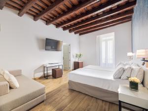 Un dormitorio con una gran cama blanca y un sofá. en H10 Raco del Pi, en Barcelona