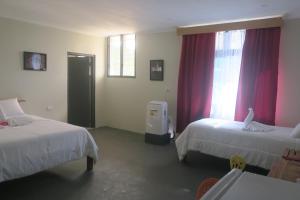 吉佐Zaru Hotel的客房设有两张床和一个带红色窗帘的窗户。 更多22张照片