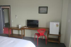 吉佐Zaru Hotel的客房设有书桌、电视和红色椅子