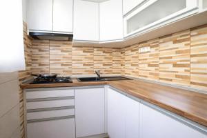 una cucina con armadietti bianchi e una parete in legno di Comfort 14 Stylish City Apartment a Miskolc