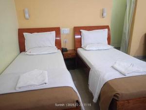 two beds in a hotel room with white sheets and pillows at Challa Residency in Rājahmundry
