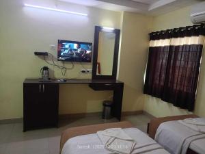 a room with a tv and a mirror and two beds at Challa Residency in Rājahmundry