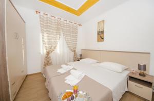 Schlafzimmer mit einem Bett mit weißer Bettwäsche und Handtüchern in der Unterkunft Guest House Mia in Split