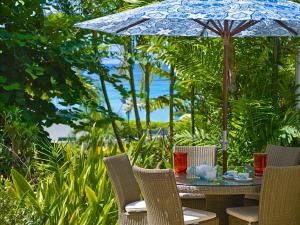 ein Tisch im Freien mit Sonnenschirm und Stühlen in der Unterkunft Beacon Hill 202 - Moonshadow by Blue Sky Luxury in Saint Peter