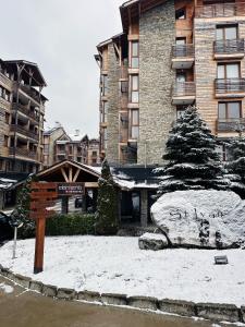 een bord voor een gebouw met sneeuw op de grond bij Bansko St Ivan Rilski Residences in Bansko