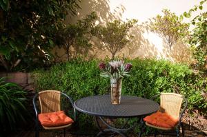 a table with a vase of flowers sitting between two chairs at a Vue Guesthouse in Somerset West