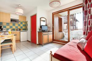 a kitchen and a living room with a table at Résidence Odalys Belle Vue in Saint-François-Longchamp