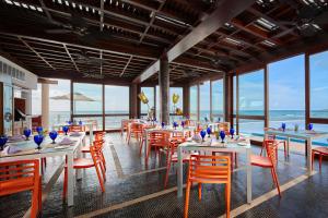 un restaurante con mesas y sillas y vistas al océano en Senses Riviera Maya - Oceanfront All inclusive Boutique hotel - Adults only, en Puerto Morelos