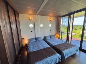 a bedroom with two beds and a balcony at Container Suite 75 in Nago