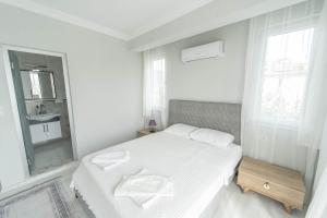 una camera da letto bianca con un letto e uno specchio di Villa Maya a Çayılı Altre 17 foto