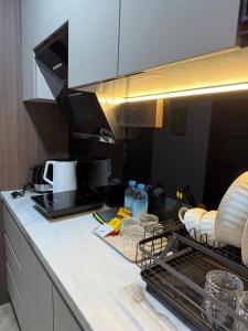 eine Küche mit einer Theke mit Geschirr und einer Mikrowelle in der Unterkunft Modern Luxury Studio at Pollux by Superstay in Batam Center + 7 Fotos