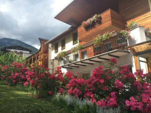 Um edifício com flores cor-de-rosa à frente. em Garni Enrosadira em Vigo di Fassa