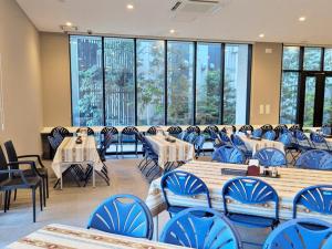 ein Esszimmer mit Tischen und Stühlen und großen Fenstern in der Unterkunft Bande Hotel Tenpozan Higashi in Osaka