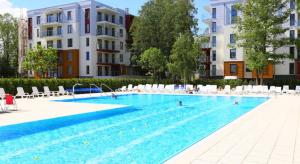 a large swimming pool with chairs and people in it at U-Stay Bond Apartament in Kołobrzeg