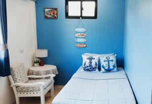 ein blaues Schlafzimmer mit einem Bett und einem Stuhl in der Unterkunft Leamsai Whisper Home in Thalang