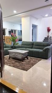a living room with green couches and a coffee table at Elite stays in Rajiv Gandhi International Airport