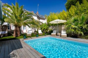 una piscina con sillas y un patio con sombrilla en Villa la Ruche, en La Baule