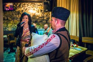 a woman standing next to a man singing into a microphone at Family hotel Valchanovata Kashta in Fotinovo