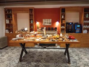 a large wooden table in a room with a kitchen at The Originals Boutique, Grand Hôtel Saint-Pierre, Aurillac in Aurillac