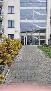 ein großes weißes Gebäude mit einem Gehweg davor in der Unterkunft Sadyba Apartament in Nowy Sącz