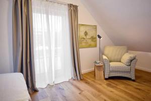 een slaapkamer met een stoel en een groot raam bij Die-perfekte-Ferienvilla in Butjadingen