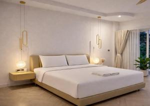 a bedroom with a large white bed with two lamps at The Escape Kamala in Kamala Beach