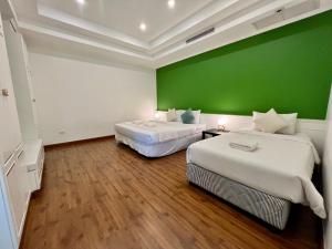 twee bedden in een kamer met een groene muur bij Abode Boutique Resort - Hua Hin in Hua Hin +49 foto's