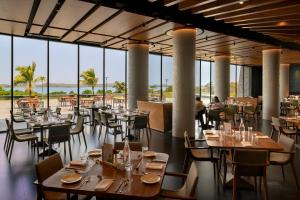 纳西克Aria Resort & Spa的一家有桌椅和大窗户的餐厅