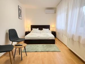 een slaapkamer met een bed, een tafel en een stoel bij Zama Apartman in Hajdúszoboszló +24 foto's