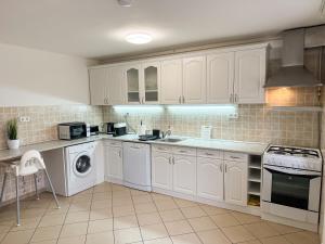 een keuken met witte kasten en een wasmachine en droger bij Zama Apartman in Hajdúszoboszló
