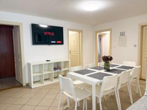 een eetkamer met een witte tafel en witte stoelen bij Zama Apartman in Hajdúszoboszló