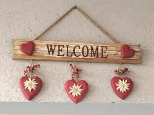 ein Willkommensschild mit Herzen und ein Zeichen, das Willkommen heißt in der Unterkunft Garni Enrosadira in Vigo di Fassa