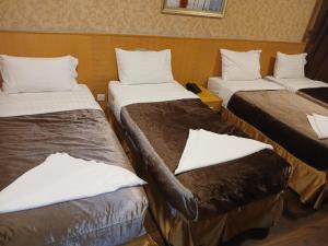 a room with three beds with white pillows at فندق رمال الخليج in Makkah