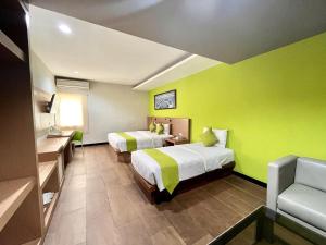 two beds in a room with green walls at Hotel Candi Indah Akpol Semarang in Semarang +33 photos