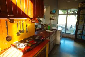 una cucina con piano cottura e parete gialla di The River Trail Cottage by The StayCationer a Rājpur Altre 18 foto