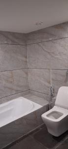een badkamer met een wit toilet en een bad bij Hotel Beral in Ahmedabad