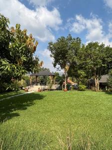 a field of grass with a gazebo and trees at Garden house in Kajansi +4 photos