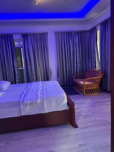 a bedroom with a bed and a chair and curtains at Garden house in Kajansi