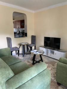 a living room with a couch and two tables and a tv at Pazurihome in Embu