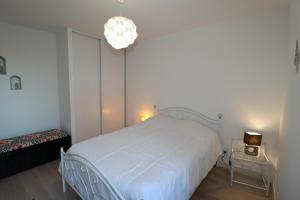 ein Schlafzimmer mit einem weißen Bett und einem Kronleuchter in der Unterkunft L'Aigue Marine by TAH - Top emplacement & Parking in Pornichet