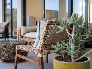 a wicker chair sitting next to a potted plant at Christiana Lodge in Plettenberg Bay