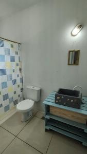 a bathroom with a toilet and a table with a suitcase at Coração do Mar in Cayru